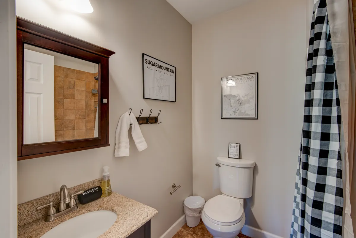 A bright and tidy full bathroom with a vanity, mirror, sink, and towel rack, accented by framed maps. The space is organized and modern, providing a refreshing environment for cleanup after a day outdoors.