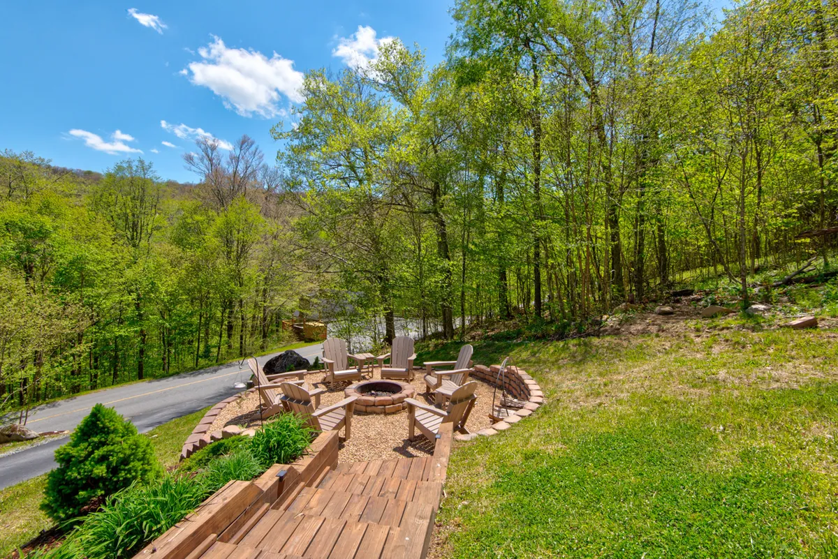 An inviting outdoor fire pit area surrounded by wooden seating and lush greenery. The setting feels private and cozy, ideal for socializing, enjoying a warm fire, or taking in the night sky.