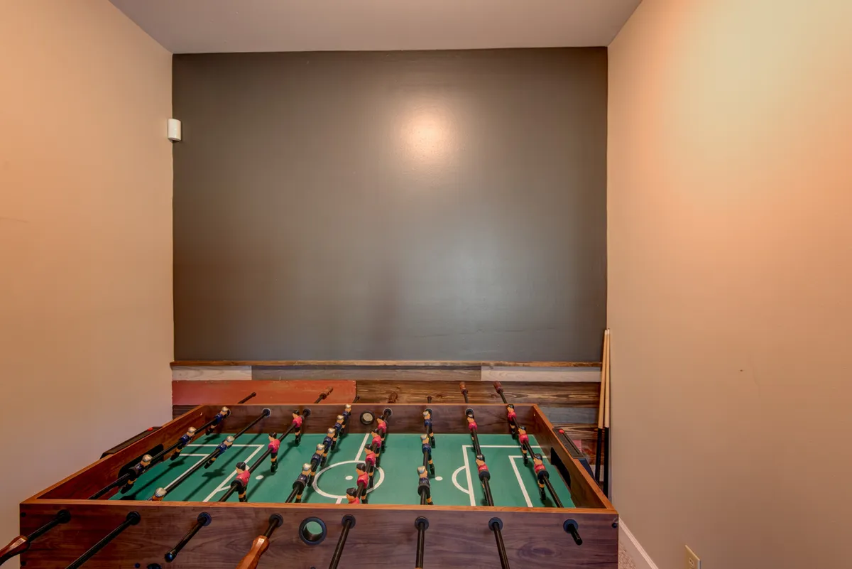 A foosball table sits as the focal point in a bright, playful space, inviting friendly competition and group fun. The casual atmosphere suggests this is a hub for games and laughter after outdoor adventures.